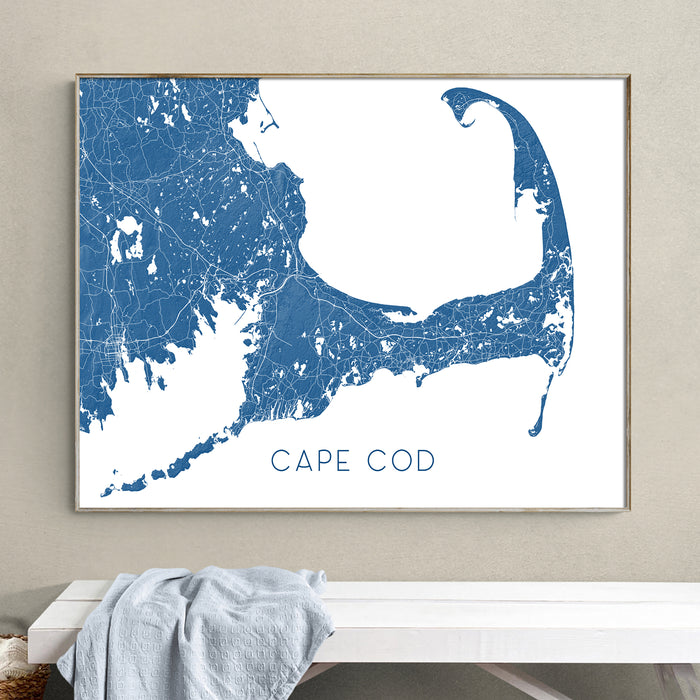 Framed map of Cape Cod on a wall above a white bench.
