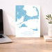 Map of Cape Cod, Martha's Vineyard, and Nantucket on a desk with a laptop and plant.