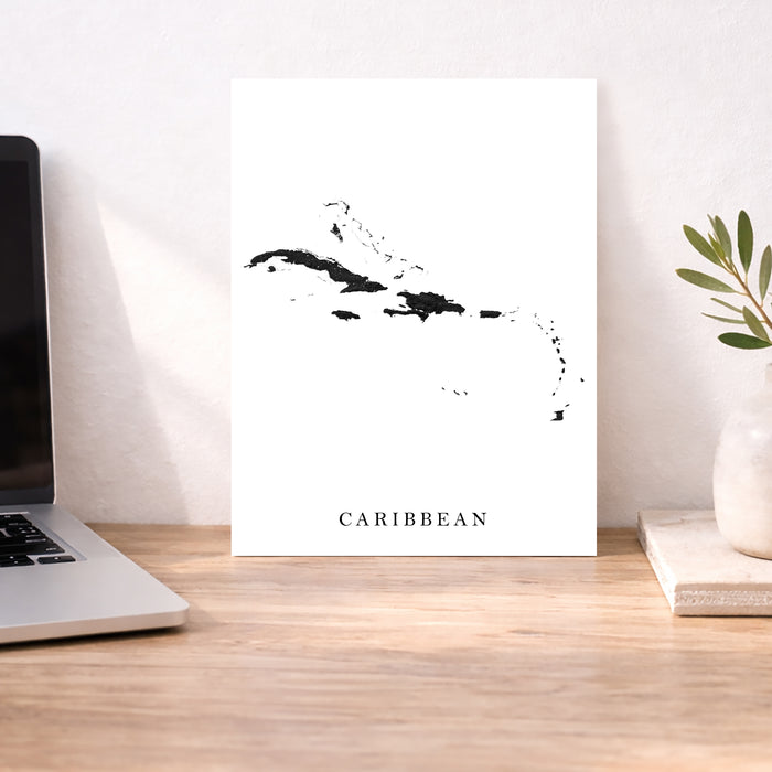 Map of the Caribbean on a white background next to a laptop on a wooden desk.