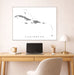 Framed map of the Caribbean on a wall above a desk with a laptop and lamp.