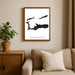 Framed map of Cayman Islands on a wall above a sofa with a plant beside it.