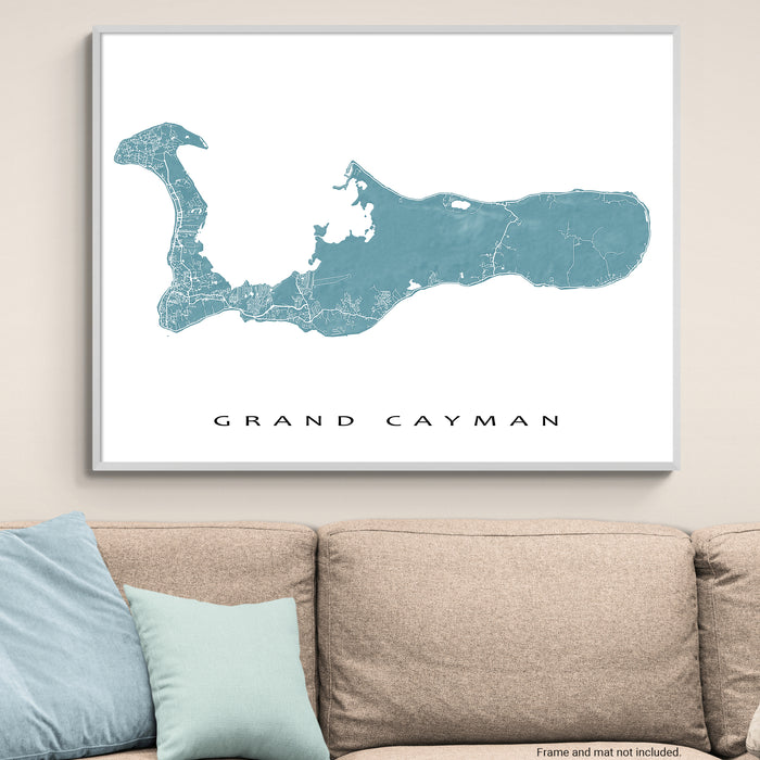 Framed map of Grand Cayman on a wall above a beige sofa with light blue pillows.