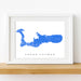 Framed map of Grand Cayman on a white wall with a wooden shelf.