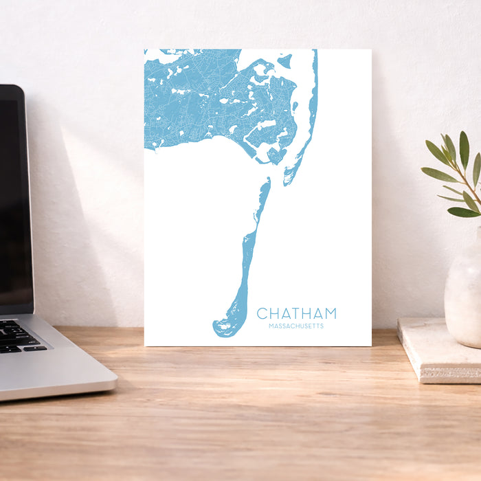 Map poster of Chatham, Massachusetts on a desk with a laptop and plant.