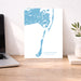 Map poster of Chatham, Massachusetts on a desk with a laptop and plant.