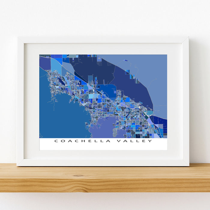 Framed map of Coachella Valley with a white border on a wooden surface.