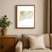 Framed map of Connecticut on a wall above a beige sofa with a plant beside it.
