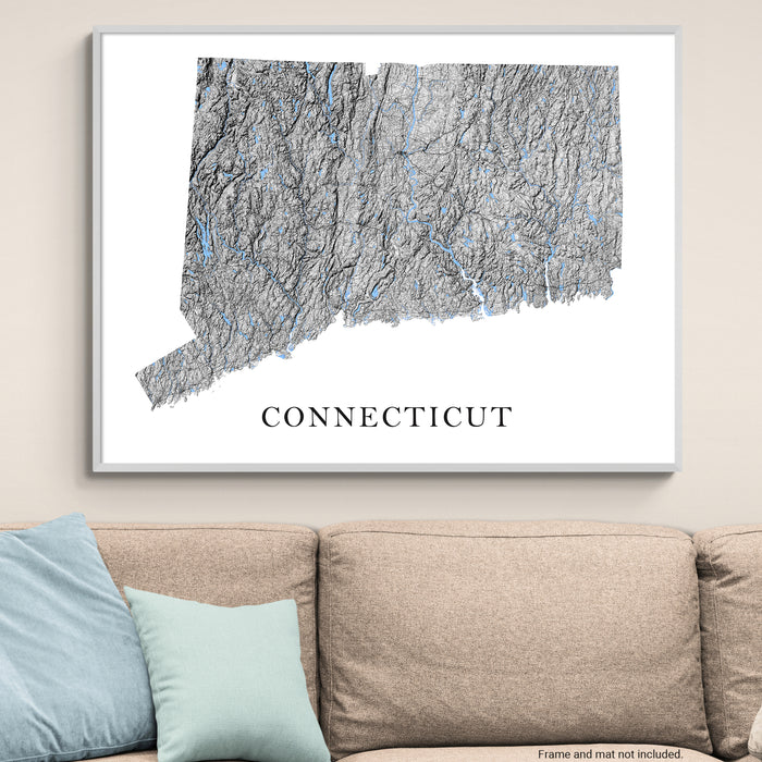 Framed map of Connecticut on a wall above a beige sofa with blue pillows.