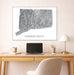Framed map of Connecticut on a wall above a desk with a laptop and lamp.