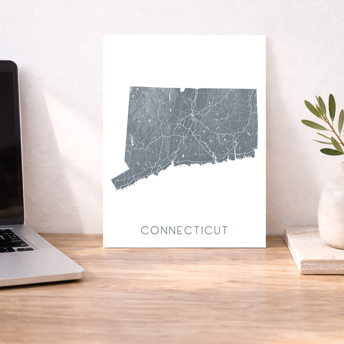 Map of Connecticut on a desk with a laptop and plant