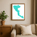 Framed map of Corfu on a wall above a sofa with a plant beside it.