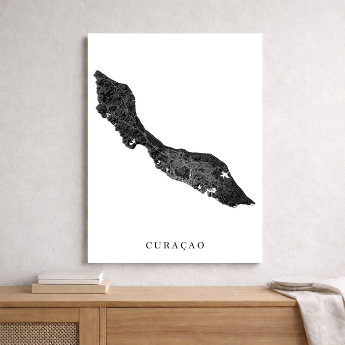 Map of Curaçao on a white wall above a wooden shelf.