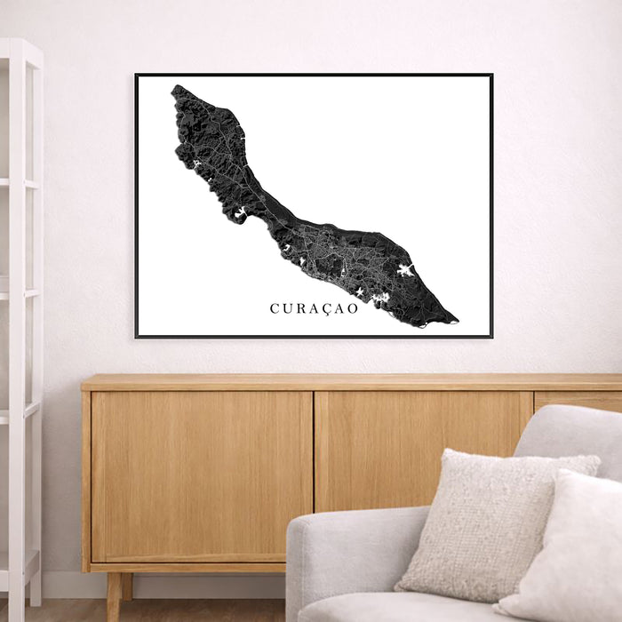 Framed map of Curaçao on a wall above a wooden cabinet and sofa.