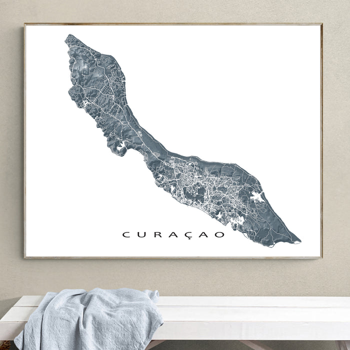 Framed map of Curaçao on a wall above a white surface.