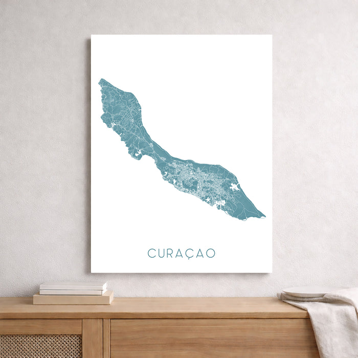 Map of Curaçao on a white wall above a wooden shelf.