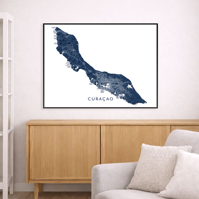 Map of Curaçao framed on a wall above a wooden cabinet and sofa.