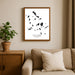 Framed map of Cyclades Islands on a wall above a sofa with a plant beside it.