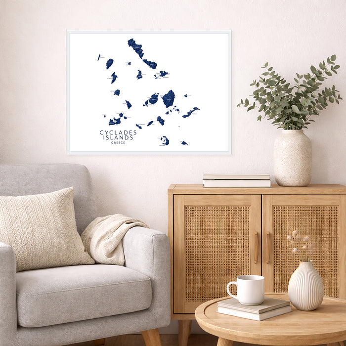 Living room with a map of Cyclades Islands on the wall, a vase with plants, and a wooden cabinet.