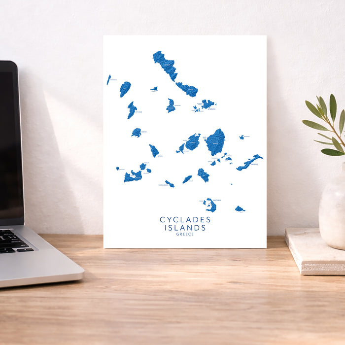Map of Cyclades Islands on a desk with a laptop and plant