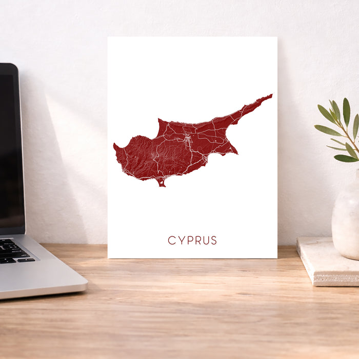 Map of Cyprus on a white background next to a laptop on a wooden desk.
