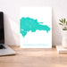 Map of the Dominican Republic on a white background, displayed on a wooden desk with a laptop and plant.