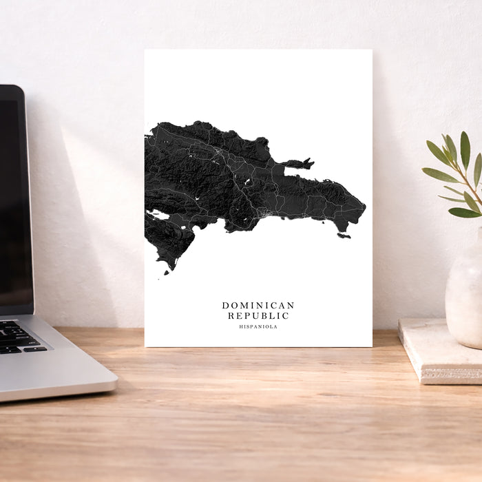 Map of the Dominican Republic on a white background next to a laptop on a wooden desk.