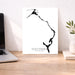 Poster of Eleuthera, The Bahamas with a black silhouette of a bird on a white background, placed on a wooden desk.