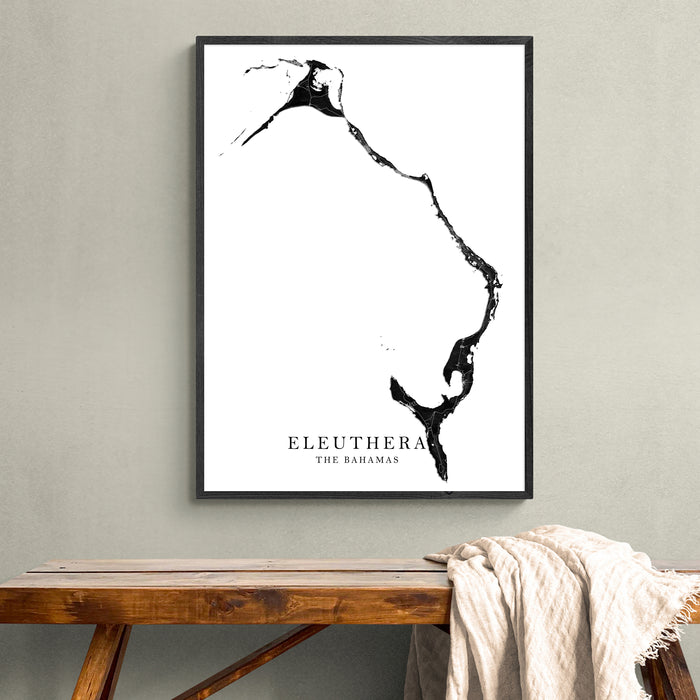 Framed map of Eleuthera, The Bahamas on a wall above a wooden bench.