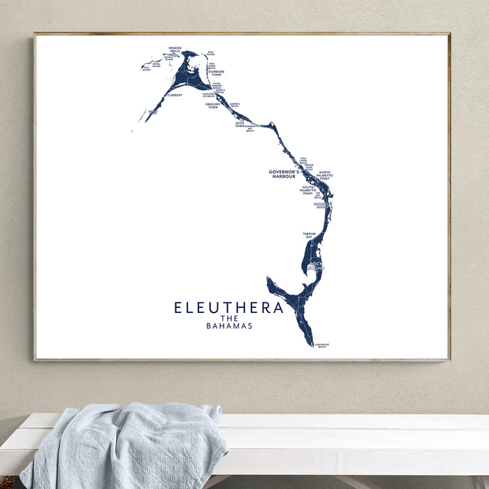 Framed map of Eleuthera, The Bahamas on a wall above a white bench.
