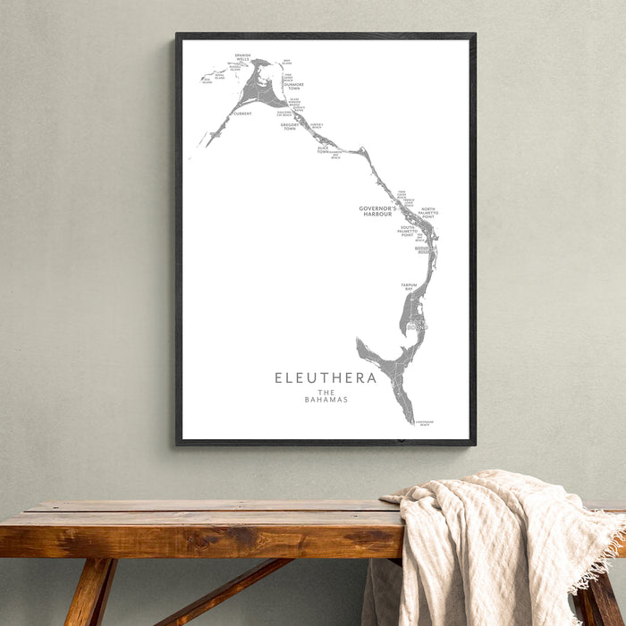 Framed map of Eleuthera, The Bahamas on a wall above a wooden bench.