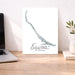 Desk with a laptop, plant, and map of Exuma, The Bahamas on a white wall.