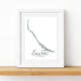 Framed map of Exumas on a white wall with a wooden shelf below.
