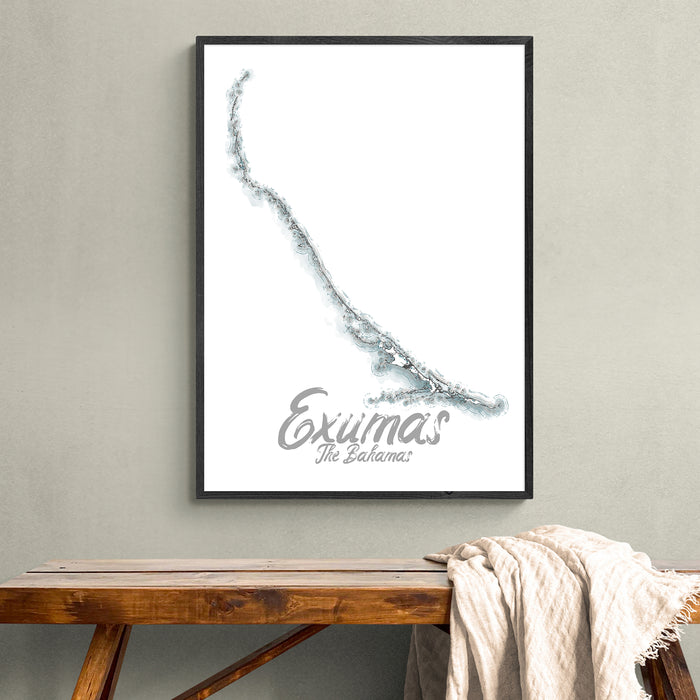 Framed artwork of Exumas, The Bahamas on a wall above a wooden bench.