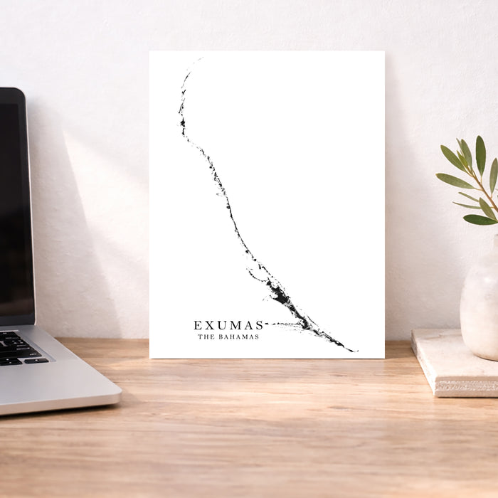 Desk with a laptop, plant, and a map of Exumas on a white background