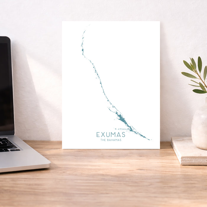 Map of Exumas, The Bahamas on a desk with a laptop and plant.