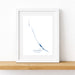 Framed map of Exumas on a white wall with a wooden shelf below.