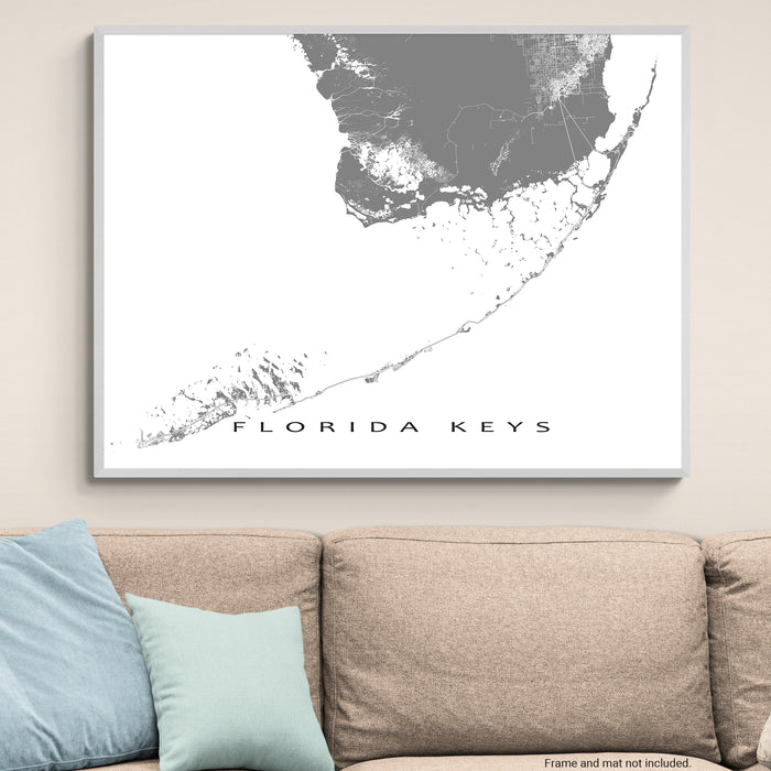 Framed map of the Florida Keys on a wall above a beige sofa with blue pillows.