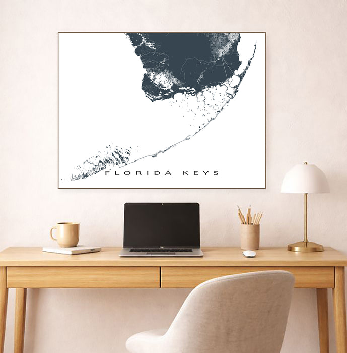 Map of Florida Keys on a wall above a desk with a laptop and lamp.