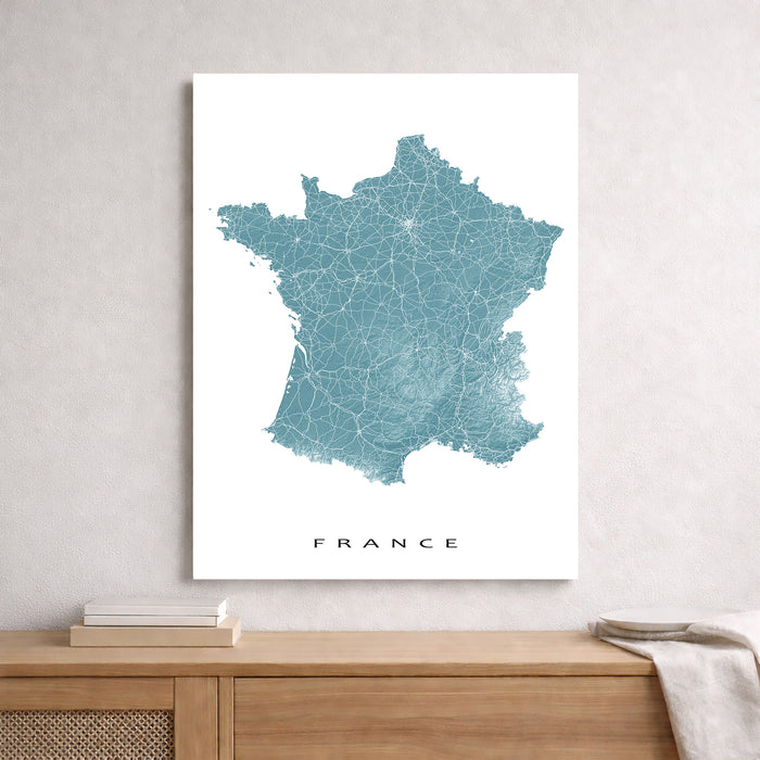 Map of France on a white wall above a wooden cabinet.