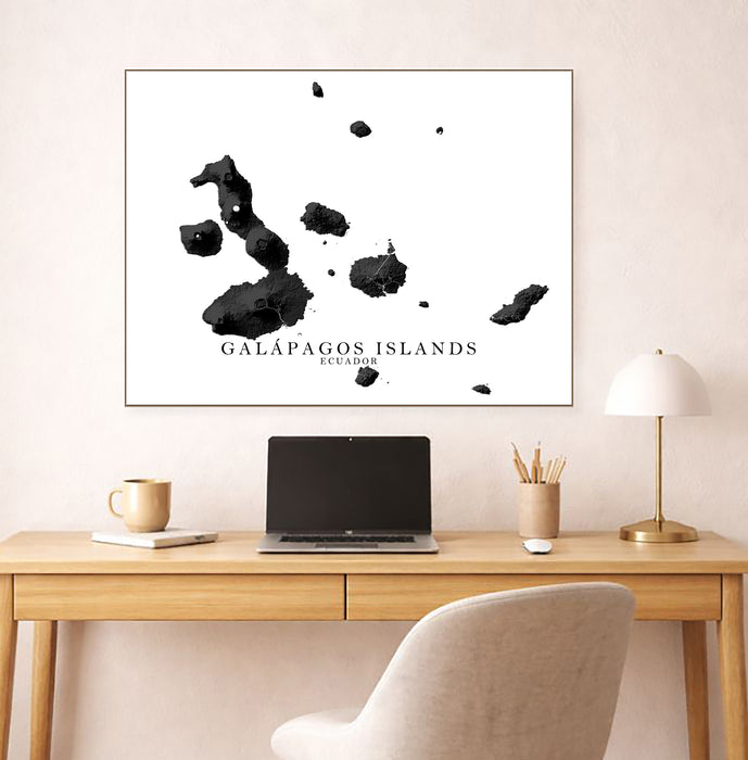 Framed map of Galápagos Islands on a wall above a desk with a laptop.