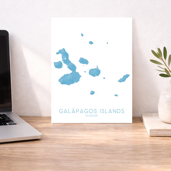 Map of Galápagos Islands on a desk with a laptop and plant.