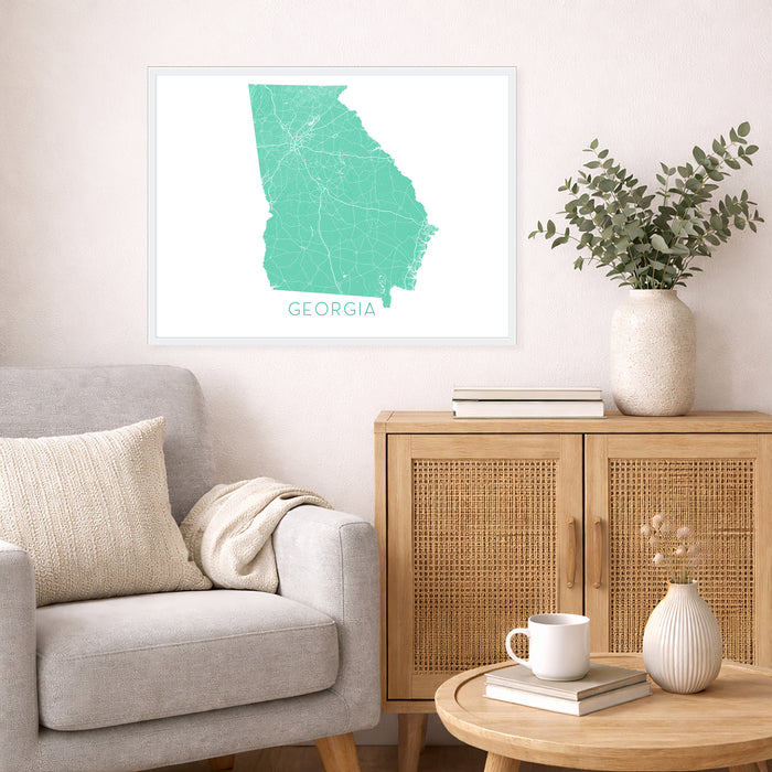 Living room with a map of Georgia on the wall, a couch, and a side table with a vase and books.