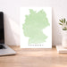 Map of Germany on a white background next to a laptop on a wooden desk.