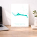 Desk with a laptop, a map of Grand Bahama, and a plant on a white wall background