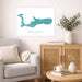 Living room with a map of Grand Cayman on the wall, a couch, and a side table with a vase and books.