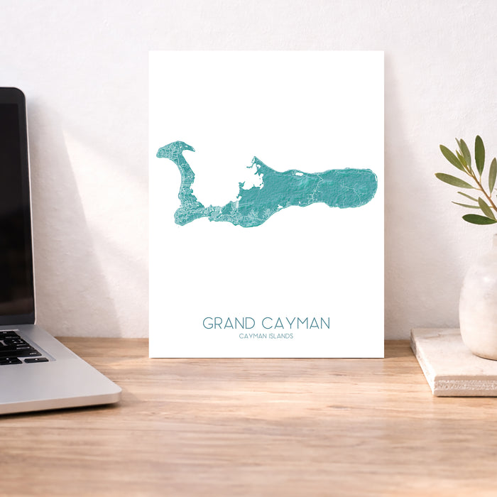 Map of Grand Cayman on a desk with a laptop and plant