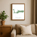 Framed map of Grand Cayman on a wall above a sofa with a plant beside it.