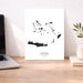 Map of Greek Islands on a white background, displayed on a wooden desk with a laptop and plant.