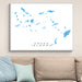 Framed map of Greek Islands on a wall above a beige sofa with light blue pillows.