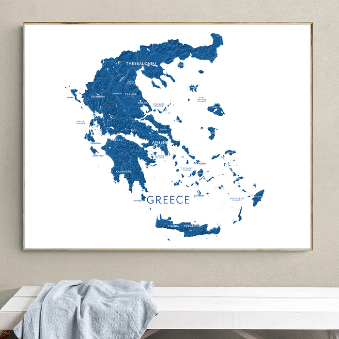 Framed map of Greece on a wall above a white bench.